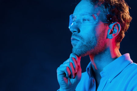 Virtual reality concept. Neon lighting. Young european man is in the dark studioの写真素材