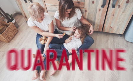 Cheerful family sitting on the floor of kitchen at quarantine time. Conception of self isolationの写真素材