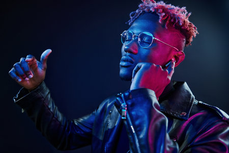 Listening to the music. Futuristic neon lighting. Young african american man in the studioの写真素材