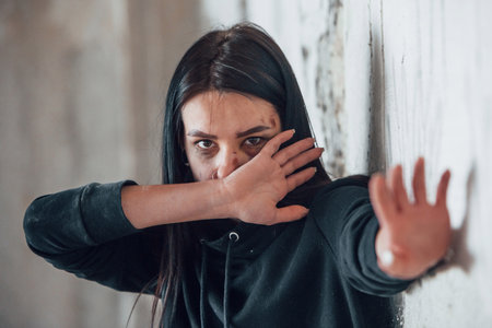 Stop the violence. Portrait of beaten young woman with bruise under eye indoors in abandoned buildingの写真素材