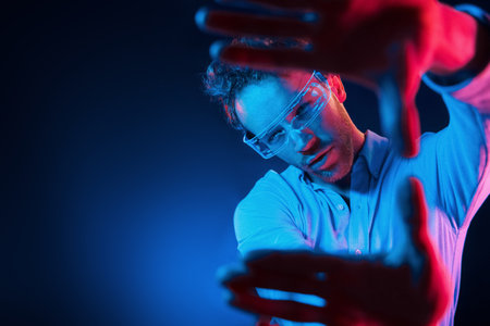 Virtual reality concept. Neon lighting. Young european man is in the dark studioの写真素材