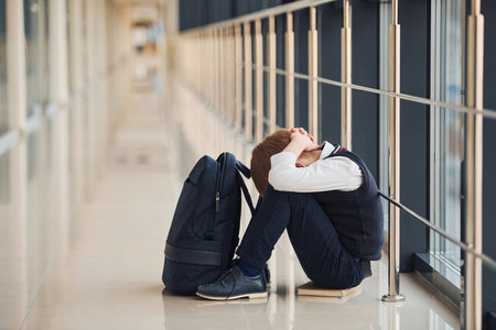 Boy in uniform sitting alone with feeling sad at school. Conception of harassmentの写真素材