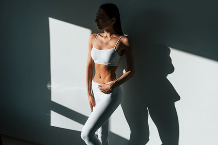 Beautiful lighting. Young caucasian woman with slim body shape is indoors at daytimeの写真素材