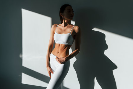 Beautiful lighting. Young caucasian woman with slim body shape is indoors at daytimeの写真素材