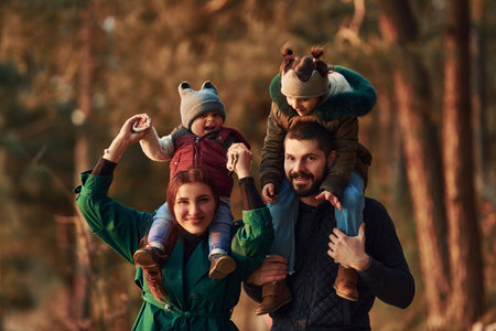 Mother and father with their little son have a walk in spring forest at daytimeの写真素材