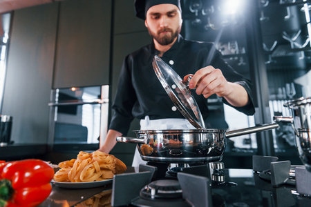 Professional young chef cook in uniform working on the kitchenの写真素材