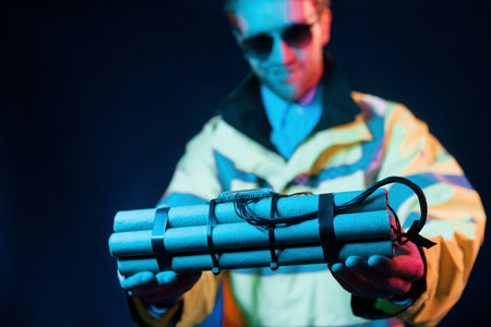 In police uniform. Neon lighting. Young european man is in the dark studioの写真素材