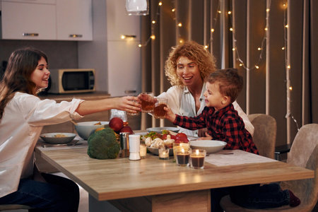Spending weekend together. Happy family of mother, daughter and son is on the kitchen at evening timeの写真素材