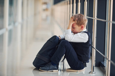 Boy in uniform sitting alone with feeling sad at school. Conception of harassmentの写真素材
