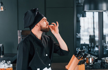 Side view of professional young chef cook in uniform that standing on the kitchen