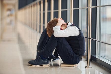 Boy in uniform sitting alone with feeling sad at school. Conception of harassmentの写真素材