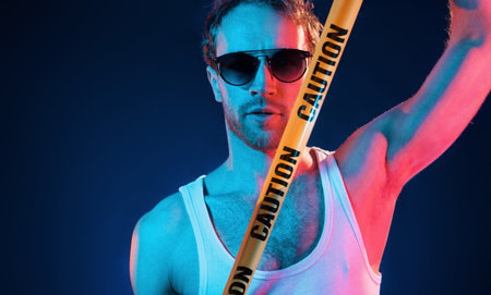 Having fun. Neon lighting. Young european man is in the dark studio