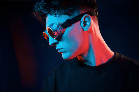 Against black background. Neon lighting. Young european man is in the dark studioの写真素材