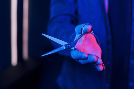 Close up view of barbers hands that holding scissors. Neon lightingの写真素材