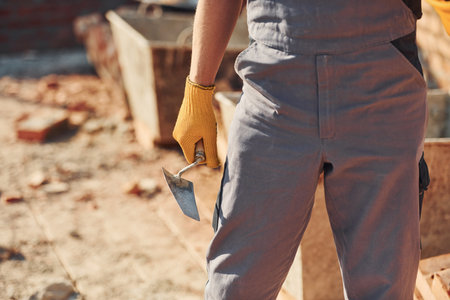 Close up view of construction worker in uniform and safety equipment standing on buildingの写真素材