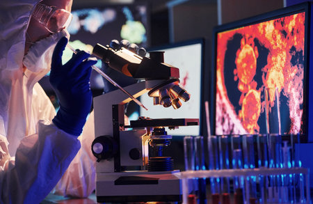 Scientist in white protective uniform near displays with data works with coronavirus and blood tubes...