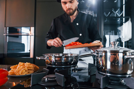 Professional young chef cook in uniform working on the kitchenの写真素材