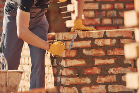 Busy with brick wall. Construction worker in uniform and safety equipment have job on buildingの写真素材