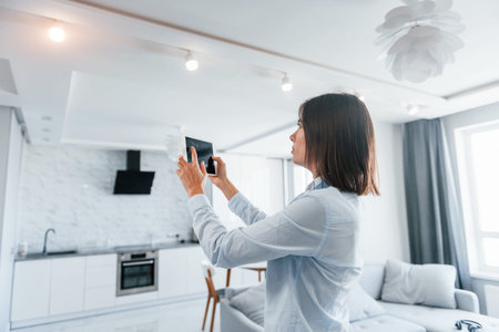 Digital tablet in hands. Young woman is indoors in smart house room at daytimeの写真素材