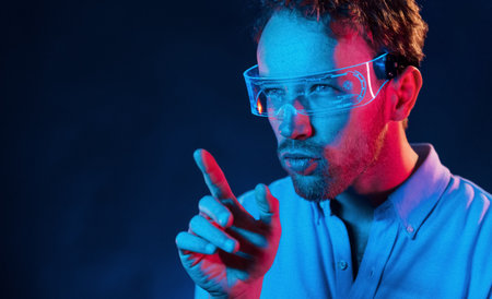 Neon lighting. Young european man is in the dark studioの写真素材