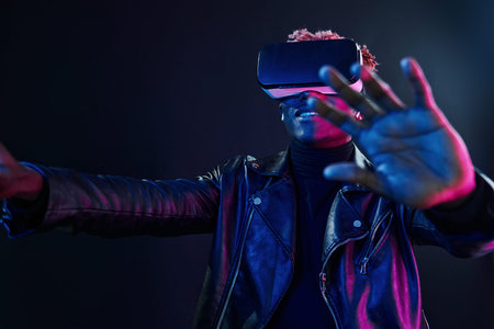Virtual reality experience. Futuristic neon lighting. Young african american man in the studio