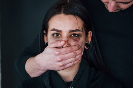 Mans hand covering her mouth. Kidnapped woman is threatened by guyの写真素材