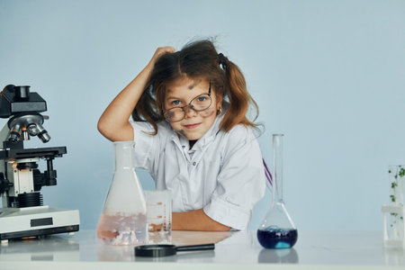 Unsuccessful experiment. Little girl in coat playing a scientist in lab by using equipmentの写真素材