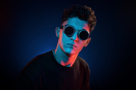 Against black background. Neon lighting. Young european man is in the dark studioの写真素材
