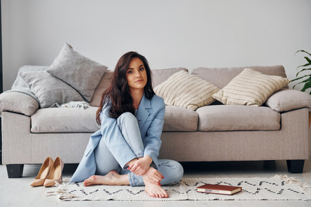 At home in blue jacket. European woman in fashionable stylish clothes is posing indoorsの写真素材