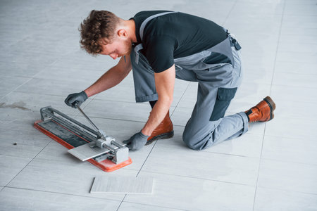 Man in grey uniform installing plate indoors in modern big office at daytimeの写真素材