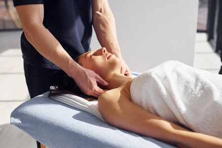 Head massage. Young woman is lying down when man doing procedure to her in spa