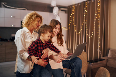 Spending weekend together. Happy family of mother, daughter and son is on the kitchen at evening...