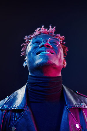 In glasses. Futuristic neon lighting. Young african american man in the studioの写真素材