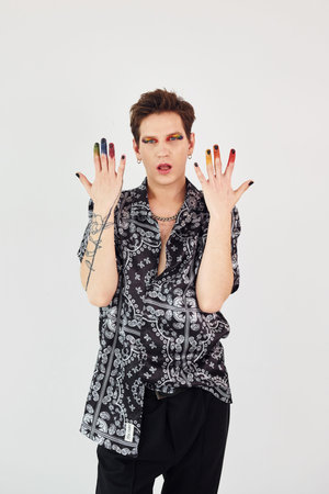 Young gay man is standing in the studio and posing for a camera. Gesturing and doing facial expressionsの写真素材