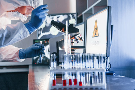 Scientist in white protective uniform works with coronavirus and blood tubes in laboratoryの写真素材