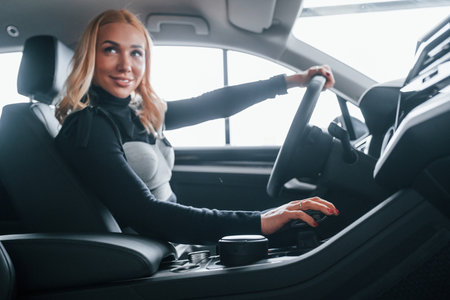 Side view of beautiful blonde in elegant clothes that sitting inside of modern carの写真素材