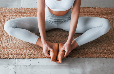 Sits on yoga mat. Woman with sportive slim body type in underwear that is in the studioの写真素材