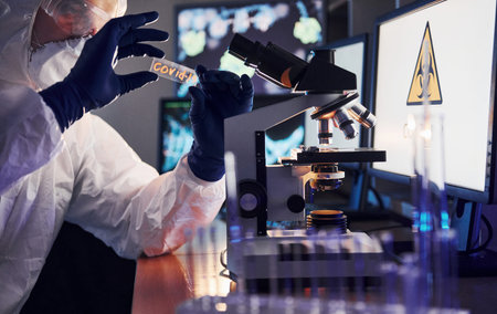 Side view of scientist in white protective uniform that works with coronavirus in laboratory