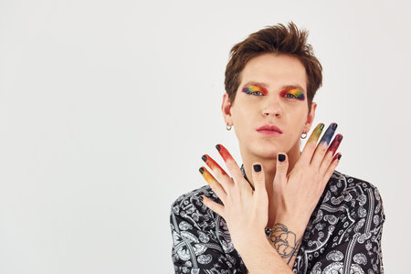 Young gay man is standing in the studio and posing for a camera. Gesturing and doing facial expressionsの写真素材