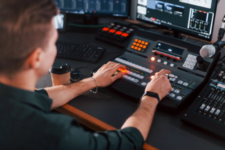 Setting the equipment. Young man is indoors in the radio studio is busy by broadcastの写真素材