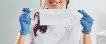 Medical mask. Portrait of professional female dentist with equipment that standing indoors