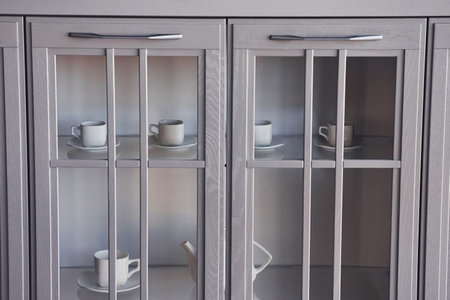 White cups standing behing glass inside in the kitchen. Empty glassesの写真素材