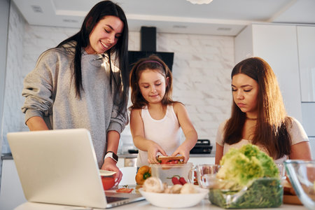 On the kitchen. Female lesbian couple with little daughter spending time together at homeの写真素材