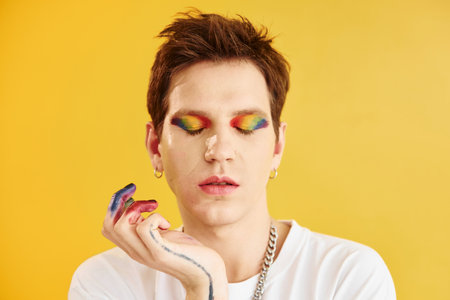 Young gay man is standing in the studio and posing for a camera. Rainbow make upの写真素材