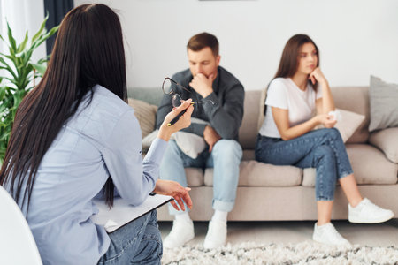 Couple is sitting on the sofa and working with female psychologistの写真素材