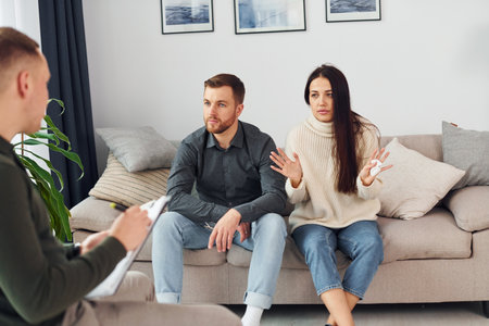 Couple is sitting on the sofa and working with male psychologistの写真素材
