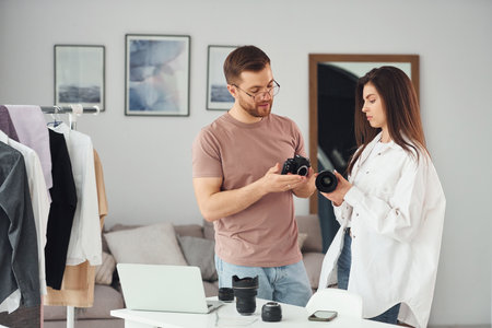 Male and female photographers talking and working in the studioの写真素材