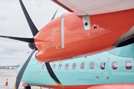 Orange and blue colored. Turboprop aircraft parked on the runway at daytimeの写真素材