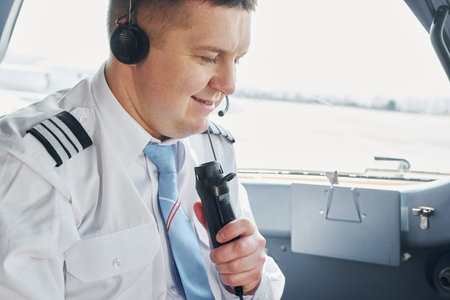 Talks to a mic. Pilot in formal wear sits in the cockpit and controls airplaneの写真素材