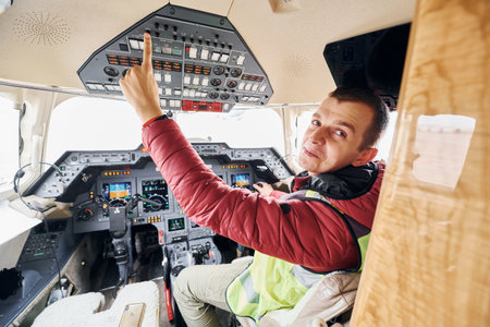 Man in casual clothes sits in the airplane cockpit and looks behindの写真素材